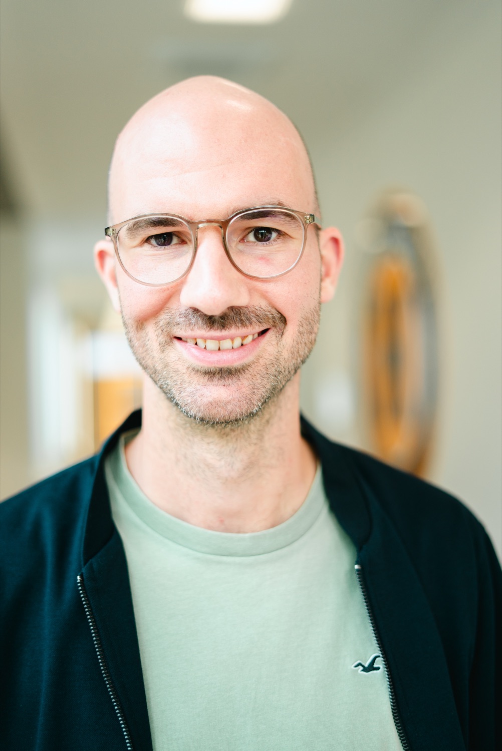 Christopher Köster lächelt in einem hellen Bürogang